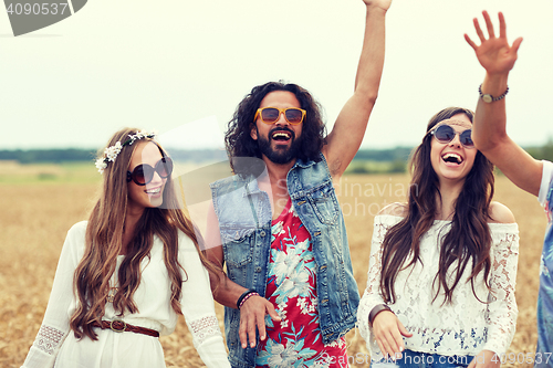 Image of happy young hippie friends dancing on cereal field