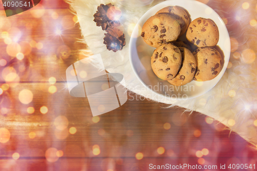 Image of christmas cookies in bowl and cones on fur rug