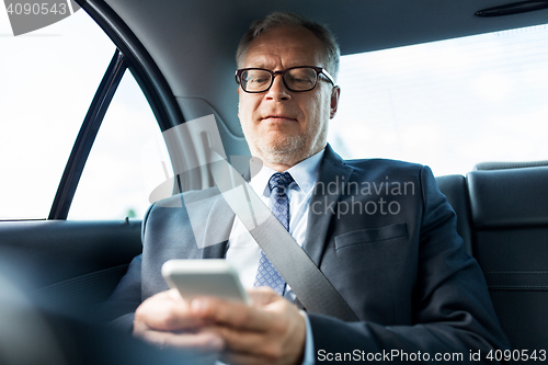 Image of senior businessman texting on smartphone in car