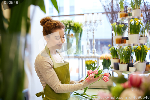 Image of smiling florist woman making bunch at flower shop