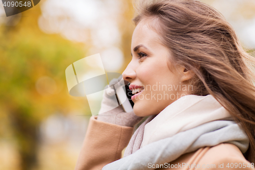Image of woman calling on smartphone in autumn park