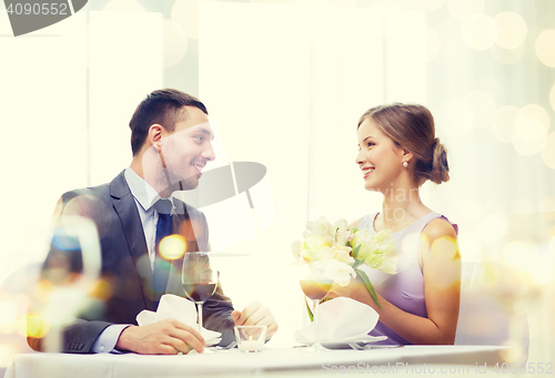 Image of smiling man giving flower bouquet at restaurant