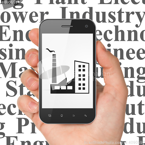 Image of Industry concept: Hand Holding Smartphone with Industry Building on display