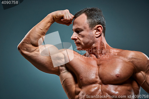 Image of torso of attractive male body builder on gray background.