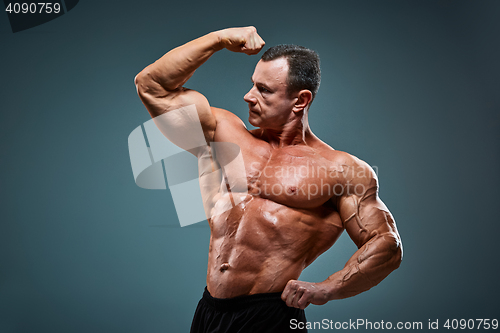 Image of torso of attractive male body builder on gray background.