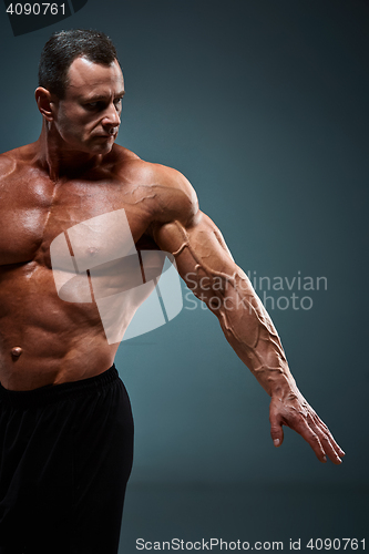 Image of torso of attractive male body builder on gray background.