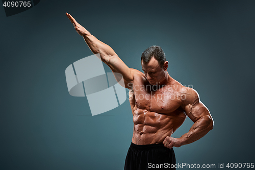 Image of torso of attractive male body builder on gray background.