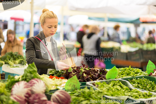 Image of Woman buying vegetable at local food market. 