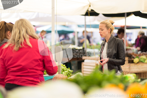 Image of Woman buying vegetable at local food market. 