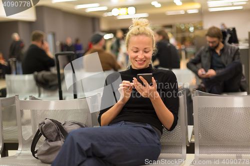 Image of Lady using smart phone while waiting at airpot departure gates.