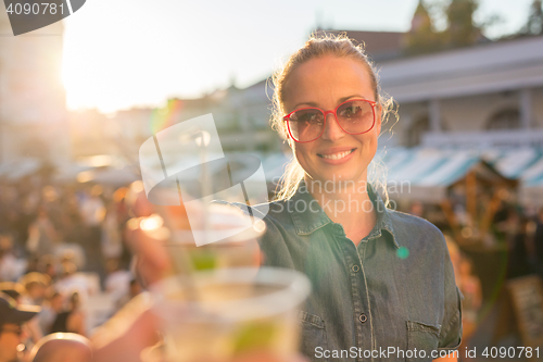 Image of Beautiful young girl toasting on outdoor urban event.