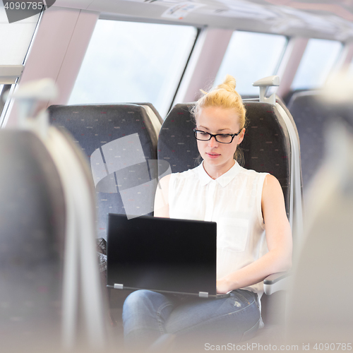 Image of Woman travelling by train working on laptop.
