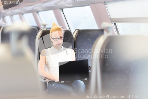 Image of Woman travelling by train working on laptop.