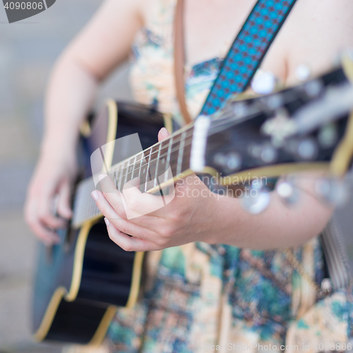 Image of Female street musician playing guitar.