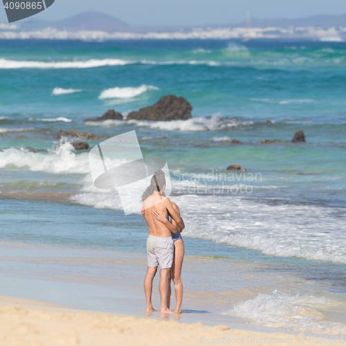 Image of Young couple embracing on sandy beach.