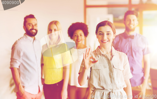 Image of happy woman showing ok over creative office team