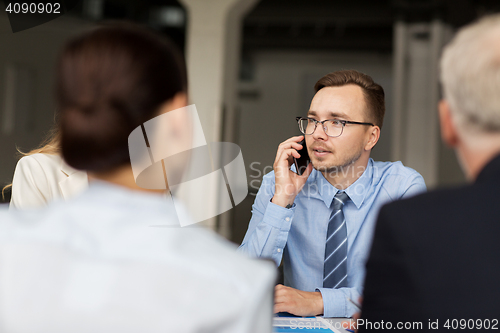 Image of businessman calling on smartphone at office