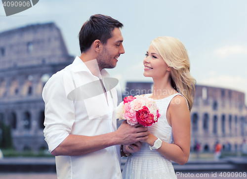Image of happy couple with bunch of flowers over coliseum