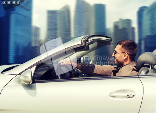 Image of happy man driving cabriolet car outdoors