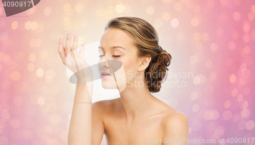 Image of woman smelling perfume from wrist of her hand