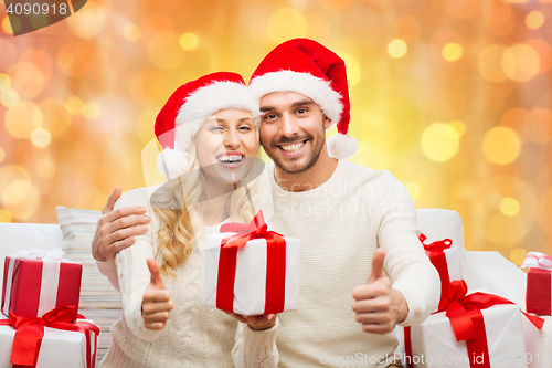 Image of happy couple with christmas gifts and thumbs up