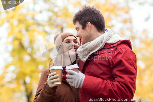 Image of happy couple with coffee walking in autumn park