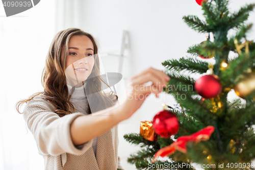 Image of happy young woman decorating christmas tree