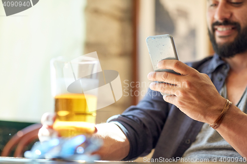 Image of close up of man with smartphone and beer at pub