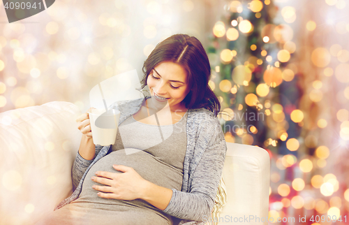 Image of happy pregnant woman with cup drinking tea at home