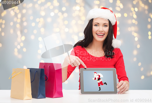 Image of woman in santa hat with tablet pc and shopping bag