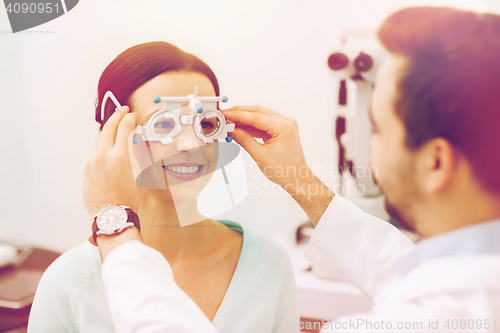 Image of optician with trial frame and patient at clinic