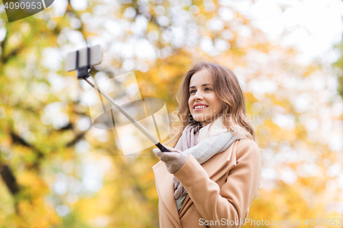 Image of woman taking selfie by smartphone in autumn park