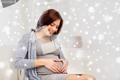Image of happy pregnant woman making heart gesture at home