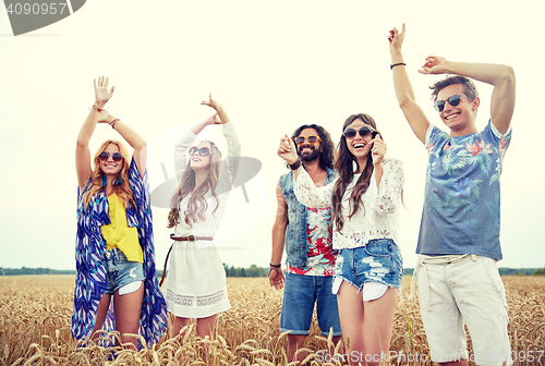 Image of happy young hippie friends dancing outdoors