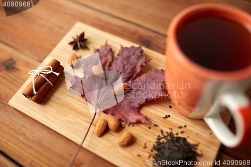 Image of cup of tea, maple leaf and almond on wooden board