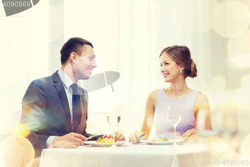 Image of smiling couple eating main course at restaurant