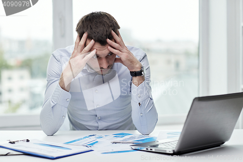 Image of stressed businessman with laptop at office