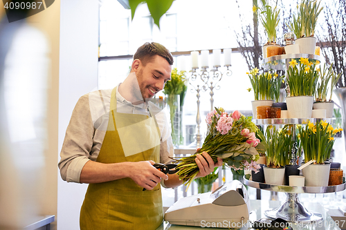 Image of smiling florist man making bunch at flower shop