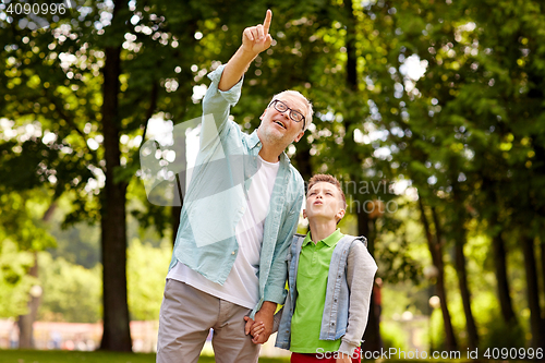 Image of grandfather and boy pointing up at summer park