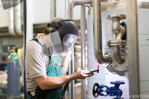 Image of Industrial worker welding in metal factory.