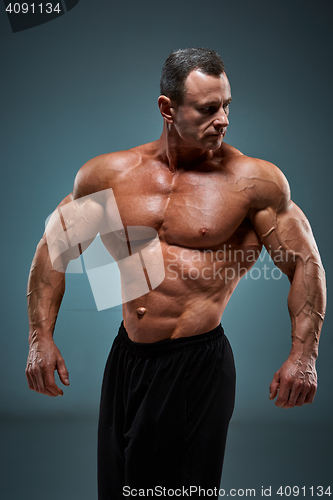 Image of torso of attractive male body builder on gray background.