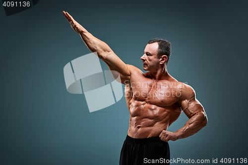 Image of torso of attractive male body builder on gray background.