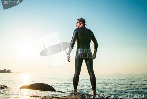 Image of Man in diving suit standing in waves