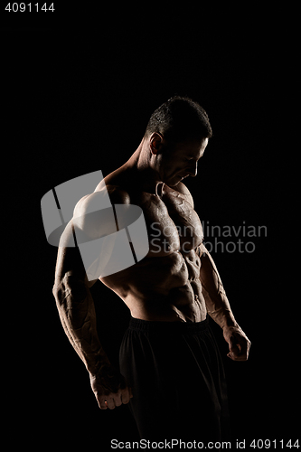 Image of torso of attractive male body builder on black background.