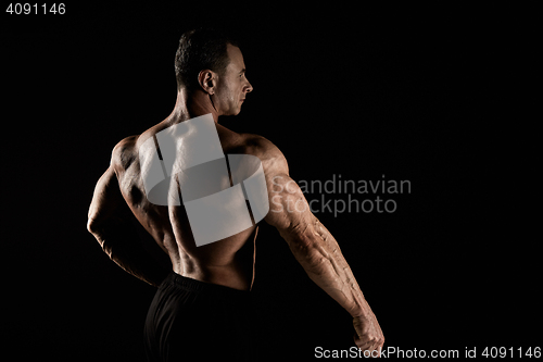 Image of torso of attractive male body builder on black background.