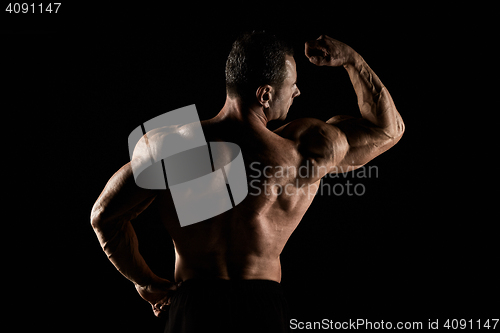 Image of torso of attractive male body builder on black background.