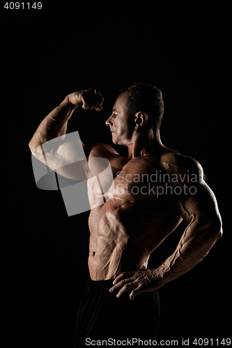 Image of torso of attractive male body builder on black background.