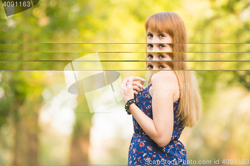 Image of Beautiful young girl turned and looked up with a smile in the frame on the background of the sunny blurred greenery