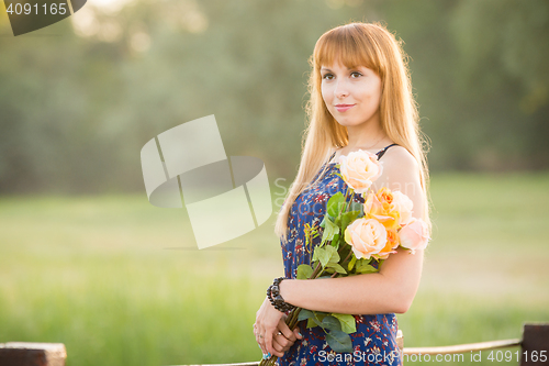 Image of Beautiful girl standing on a river bridge with a bouquet of flowers. Portrait