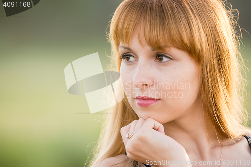 Image of Up portrait of a girl gazing to the left, creating a soft green background